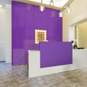 Modern reception area with a purple wall and matching reception desk.